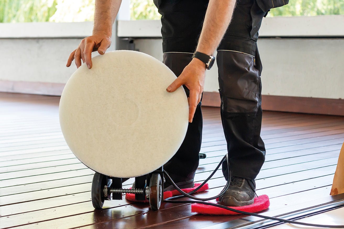 Person using a sanding machine on a wooden floor.