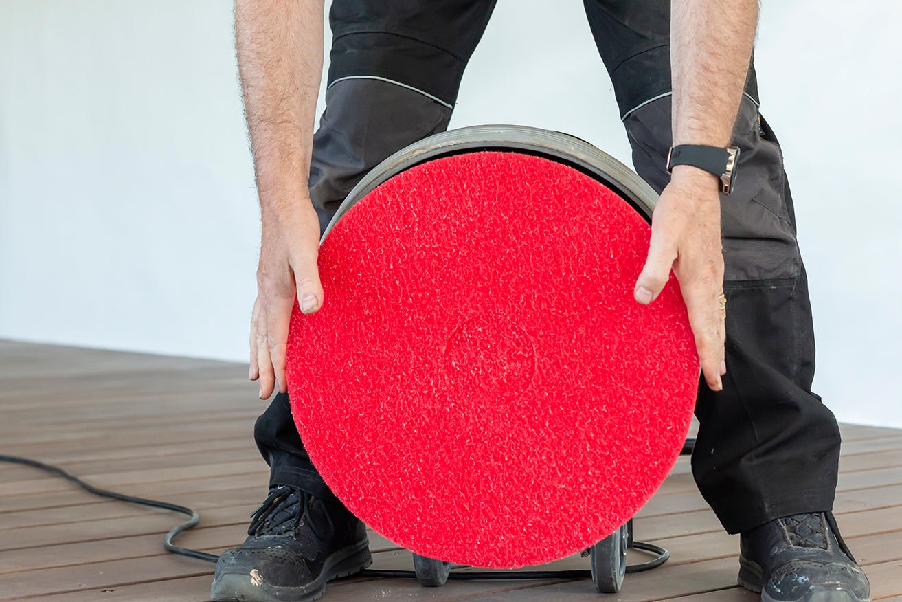 Person using a sanding machine on a wooden floor.